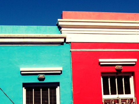 Ein türkisfarbenes und ein knallrotes Haus nebeneinander in Bo Kaap in Kapstadt, Südafrika