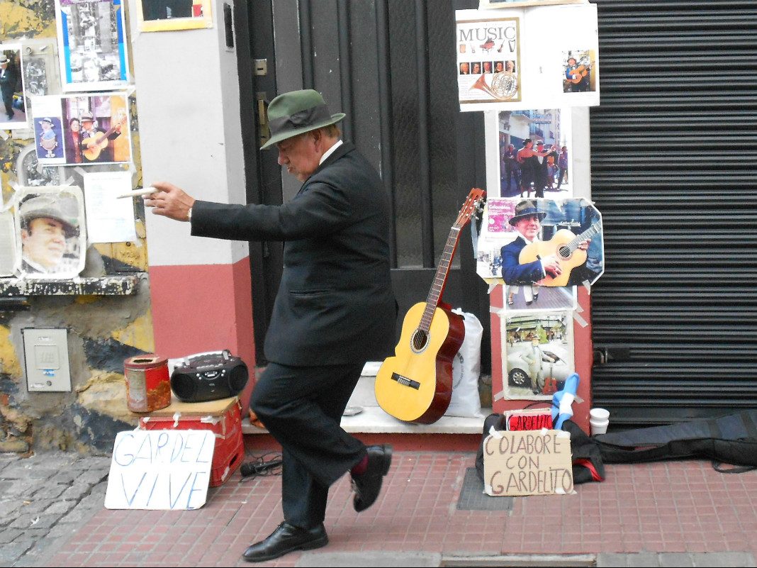 Ein Straßenkünstler mit Hut und Anzug tanzt zu Musik vom CD-Player in Buenos Aires