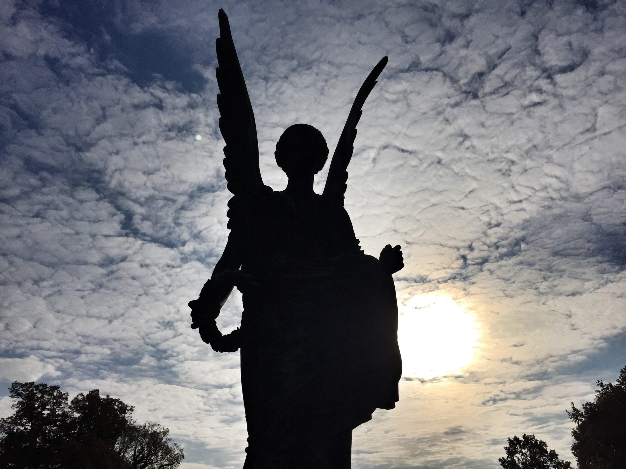 Was der Gedanke an den Tod für mein Leben bedeutet: Engelsstatue auf einem Friedhof im Gegenlicht