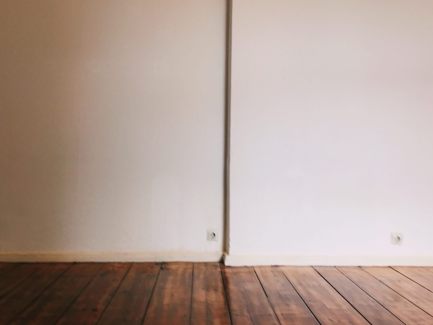 Neuanfang: Foto einer weißen Wand mit Holzboden in einer leeren Wohnung