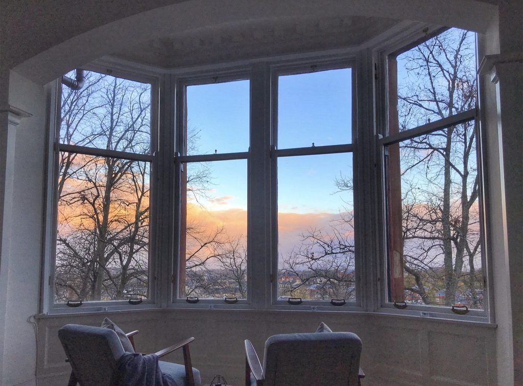 Ein neues Zuhause: Ausblick aus einem großen Erkerfenster auf einen Sonnenuntergang in Glasgow